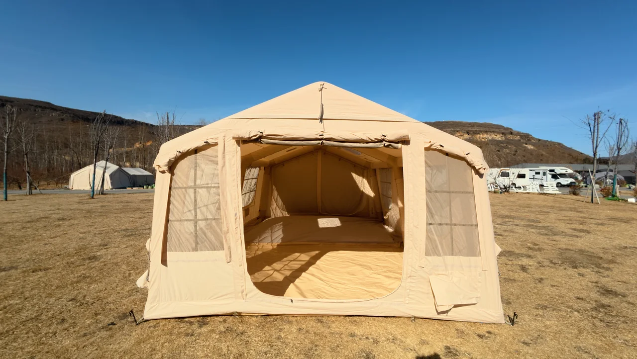 Large beige inflatable lodge with a wide front opening installed on a campsite