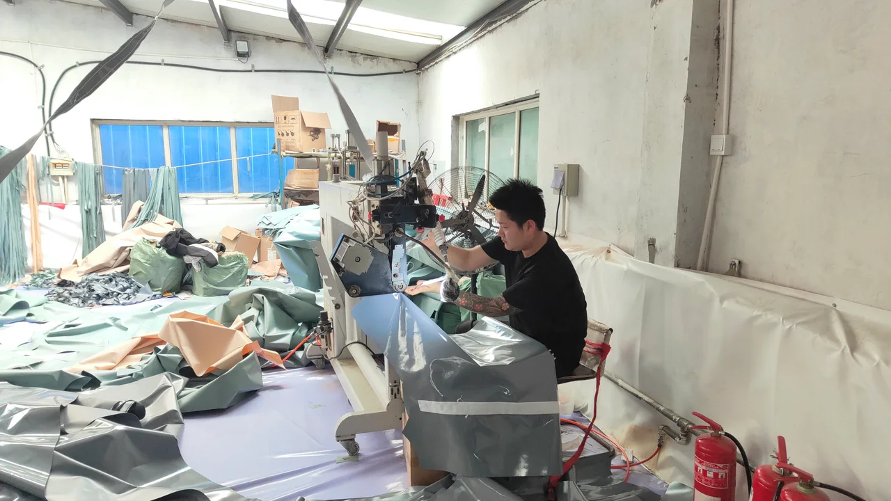 Operator fabricating coated material used for inflatable tent air-beam components