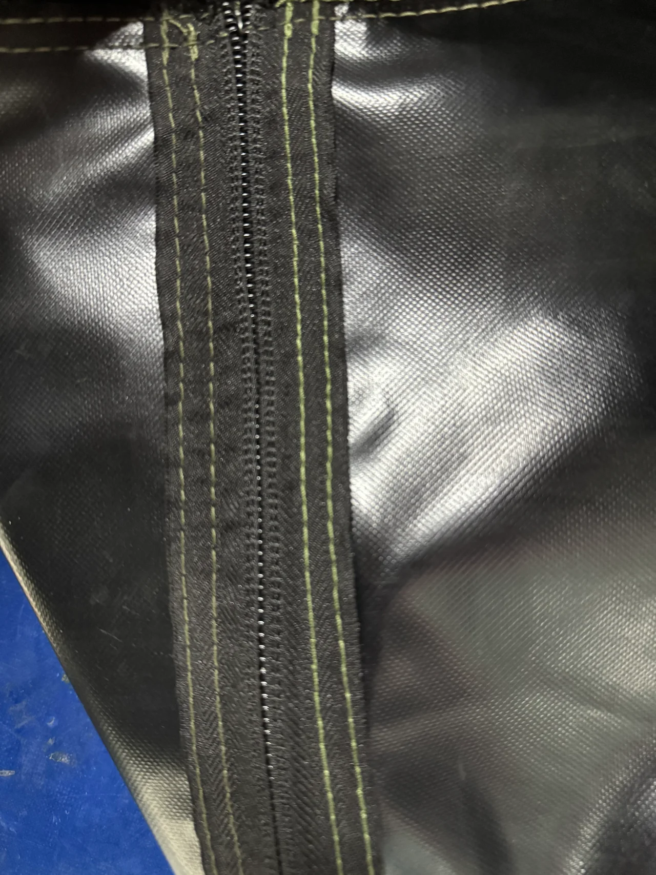 Close view of a zipper and parallel stitch lines on a coated inflatable tent component