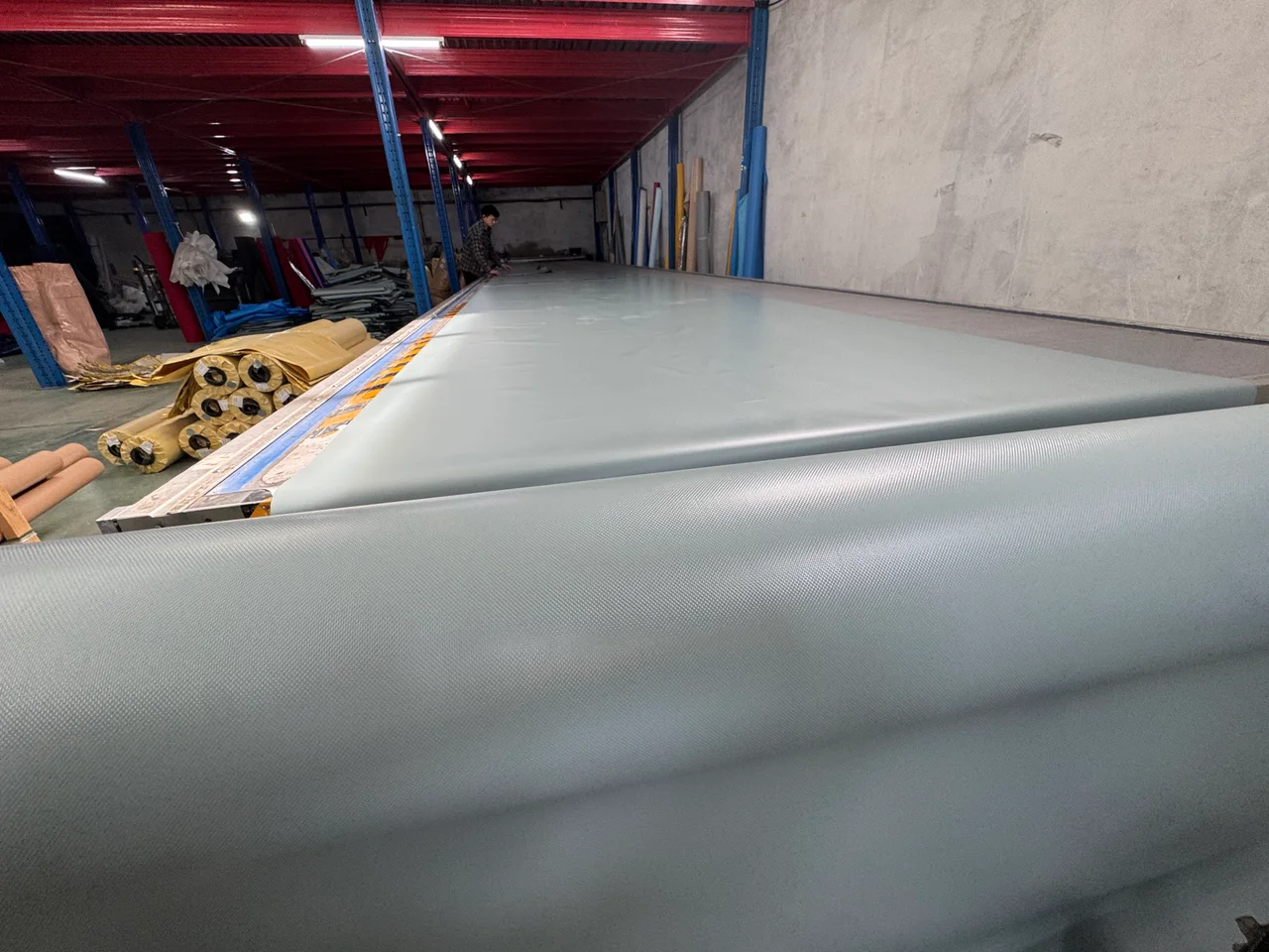 Wide coated tent material being prepared on a workshop table