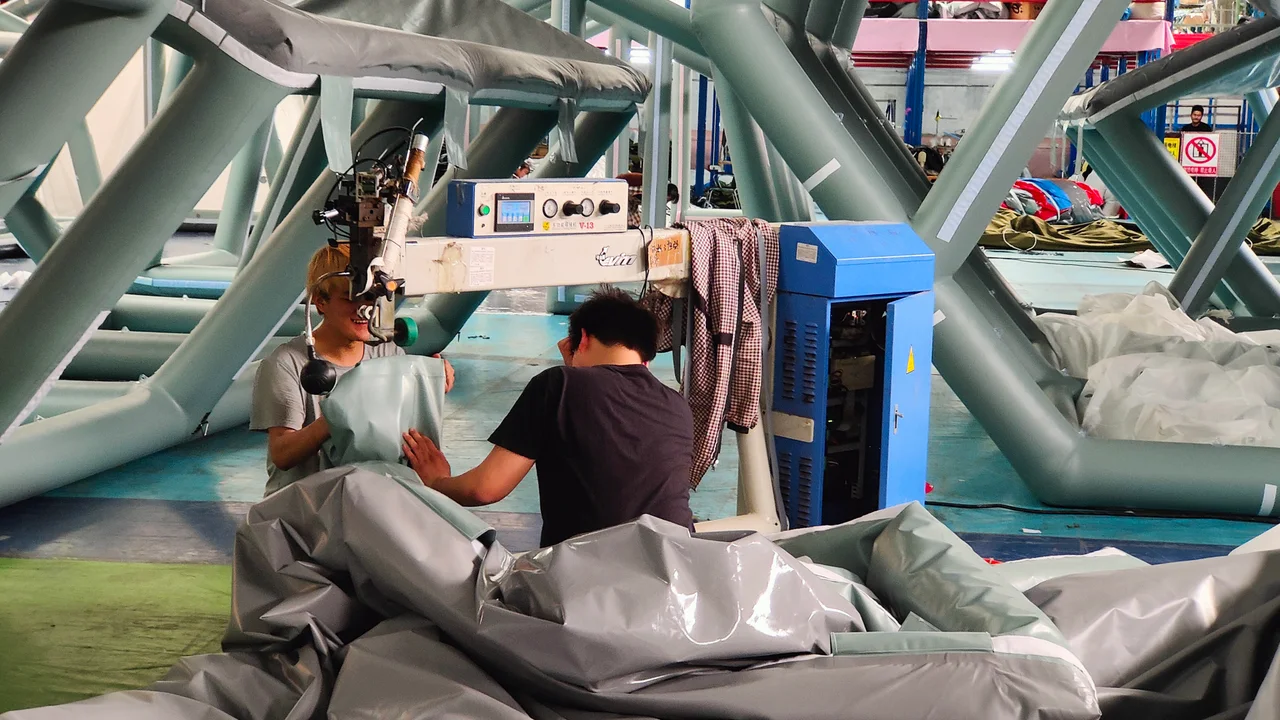 Operators joining inflatable tent air-beam material with workshop equipment