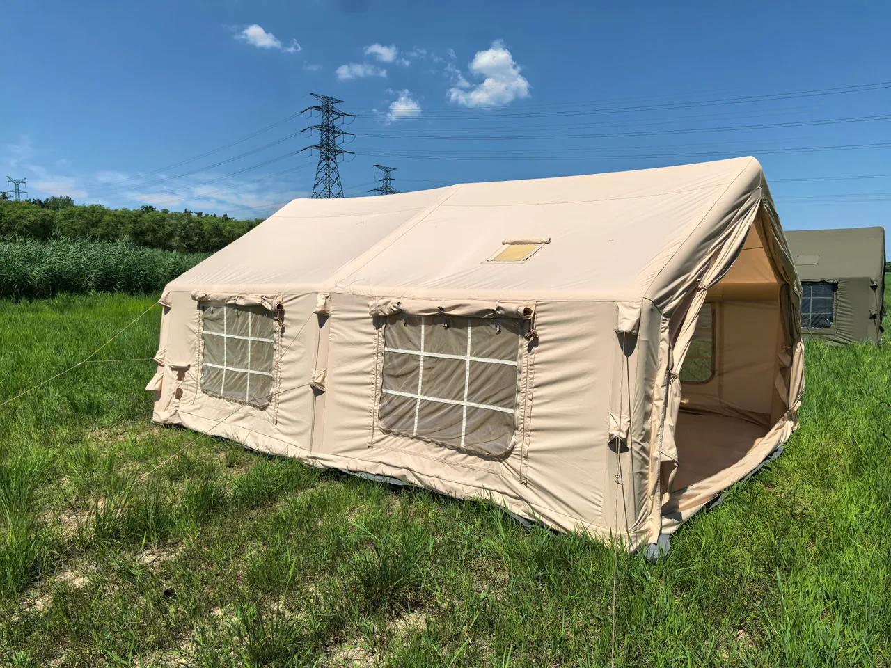Large beige inflatable camping tent with its front opening raised